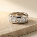 BASTION men's 10mm white gold band set with five princess cut lab grown diamonds, three quarter view on a travertine ledge